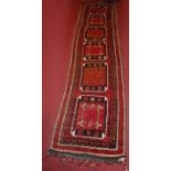 A Turkish woollen hall runner, the red ground decorated with six large medallions within multiple