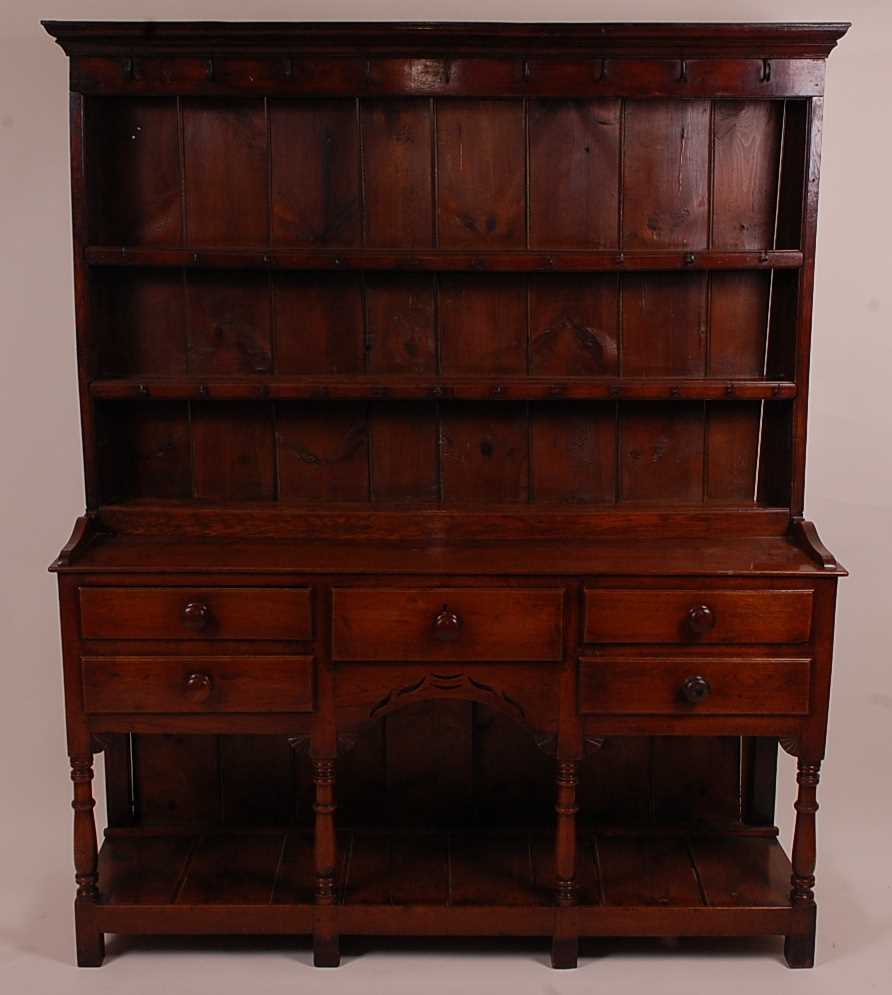 An 18th century oak dresser, the upper section having a two-tier plate rack with ironmongery to each