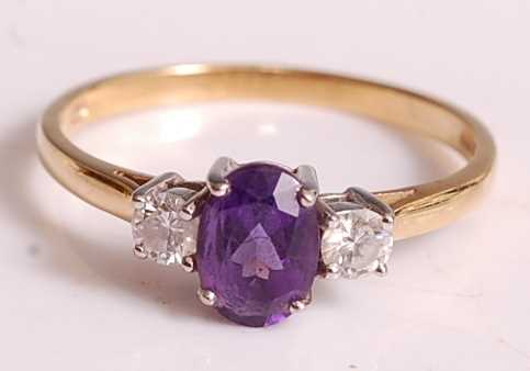 An 18ct yellow and white gold, amethyst and diamond three-stone ring, comprising a centre oval