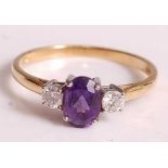 An 18ct yellow and white gold, amethyst and diamond three-stone ring, comprising a centre oval