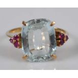 A yellow metal, aquamarine and ruby dress ring, comprising a cushion shaped aquamarine in a four-