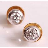 A pair of 18ct yellow and white gold, diamond single stone stud earrings, each featuring a round