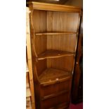 A contemporary Ercol mid-elm freestanding corner cupboard, the open shelves over single panelled