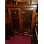 A 1920s oak freestanding double door glazed bookcase, having adjustable shelved interior on barley