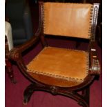 An early 20th century Spanish relief carved oak X-framed open armchair, having tan leather studded