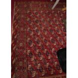 A large Persian woollen red ground Bokhara rug, the repeating central ground within trailing