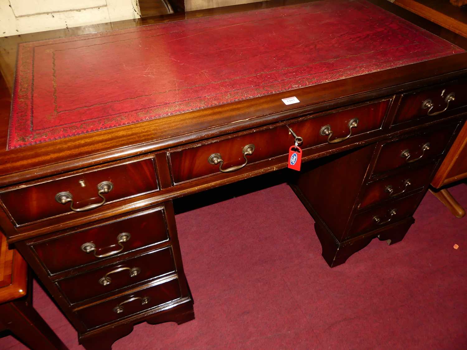 A reproduction mahogany and gilt tooled red leather inset twin pedestal writing desk, having typical