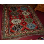 A mid 20th century Turkish woollen red ground rug, the stepped geometric lozenge decorated central