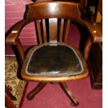 A 1930s oak slat back tub swivel desk chair, having a green leather studded pad seat on roller