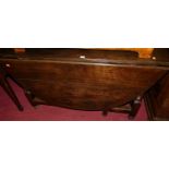 An antique joined oak drop leaf dining table, having a gate-leg action, raised on turned and