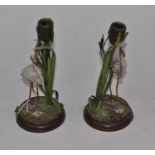 A pair of painted spelter with a bronze base table candlesticks, each sconce amongst bullrushes,