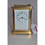 A lacquered brass cased carriage clock having a white enamel dial with Arabic numerals, signed