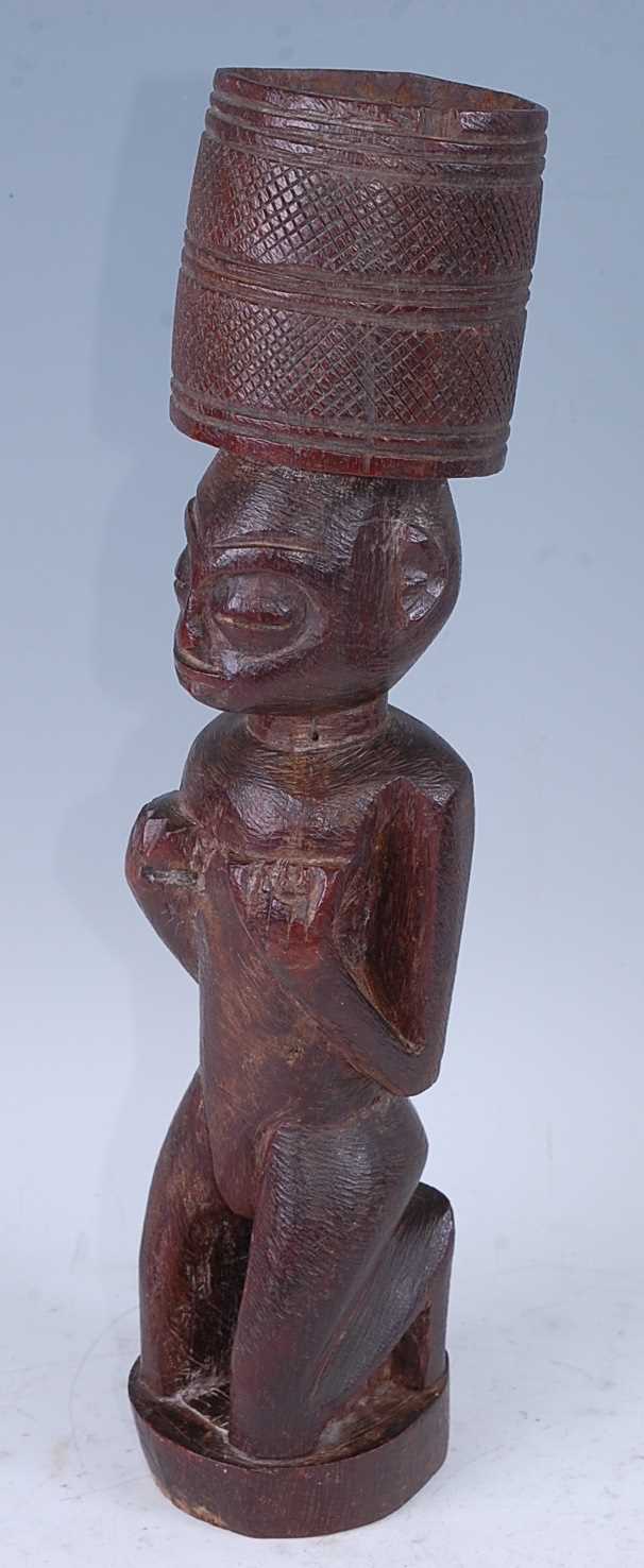 A Bateba Phuwe, carved in kneeling pose with arms upon the chest and an offerings? bowl to the top