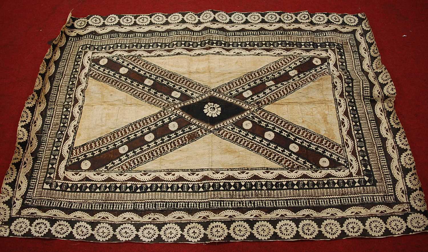 A Batik style wall hanging, having a central cross design in shades on brown and black within