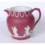 A Wedgwood crimson Jasperware jug, circa 1870, relief decorated with classical figures and swags,