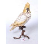 A modern cold-painted bronze model of a parakeet perched on a branch, h.30cm