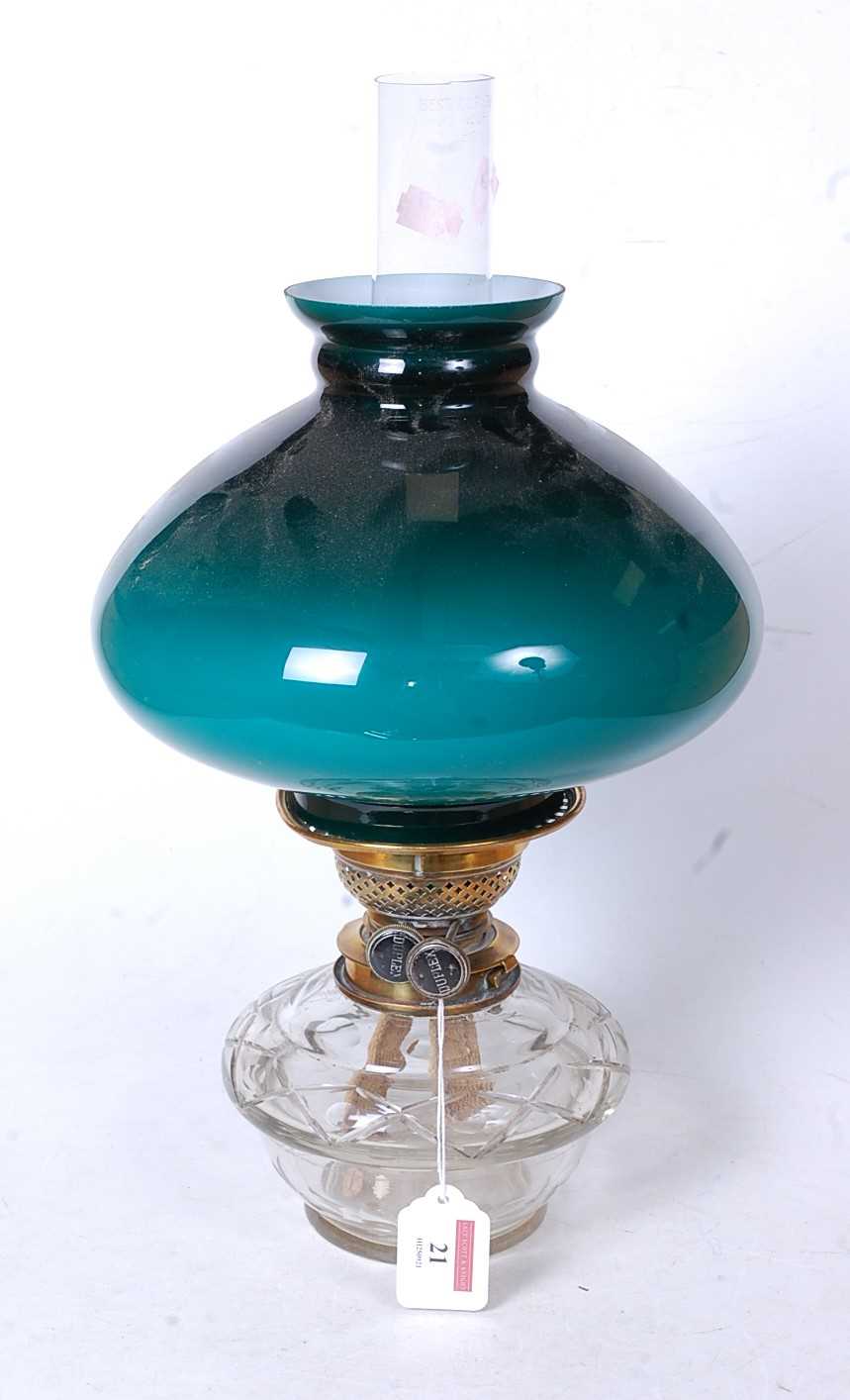 An early 20th century oil lamp, having a green opalescent glass shade, duplex burner and clear glass