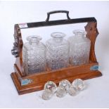 A 1920s oak three bottle tantalus, having silver plated mounts and folding locking stile, containing