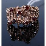 A modern yellow metal garnet set dress ring, the eight small four claw set round cut garnets set