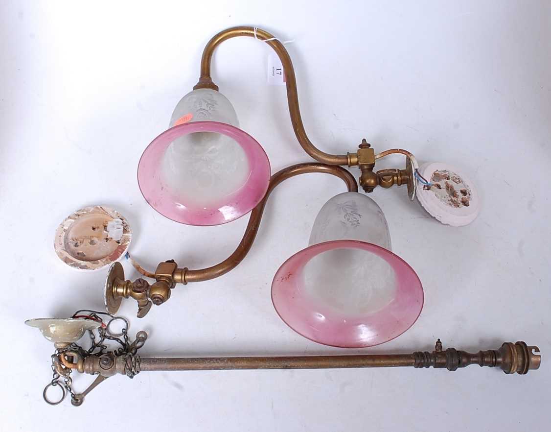 A pair of early 20th century brass single sconce wall light fittings, each having a cranberry tinted