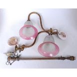 A pair of early 20th century brass single sconce wall light fittings, each having a cranberry tinted