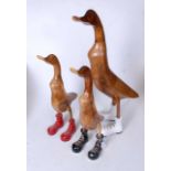 A set of three carved wooden figures, each in the form of a duck in different coloured oversized