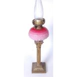 A Victorian oil lamp, having a pressed pink glass font, on a Corinthian column and stepped square