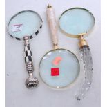 An oversized magnifying glass having a cut glass handle, together with two others similar