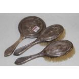 A George V silver backed hand mirror, together with a matching pair of silver backed hairbrushes, (