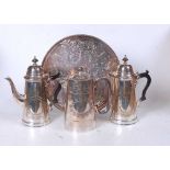 A pair of early 20th century silver plated hot water jugs, each having a domed cover, engraved body,