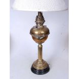 An early 20th century brass pedestal oil lamp, later converted for electricity, having a pleated