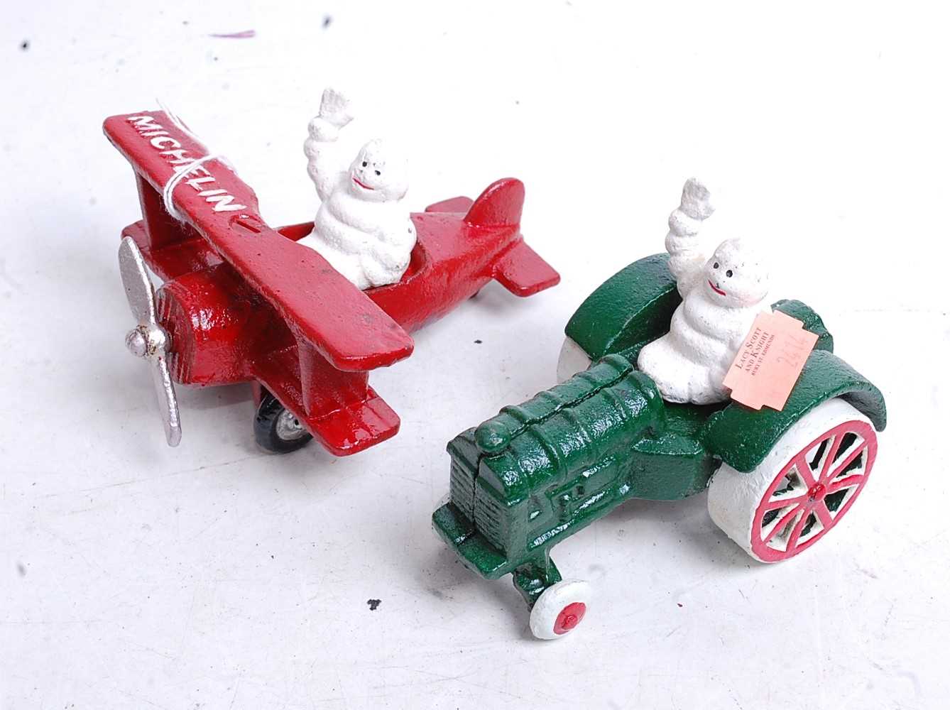 Two painted cast metal Michelin Man figures, one in a tractor, the other in an aeroplane