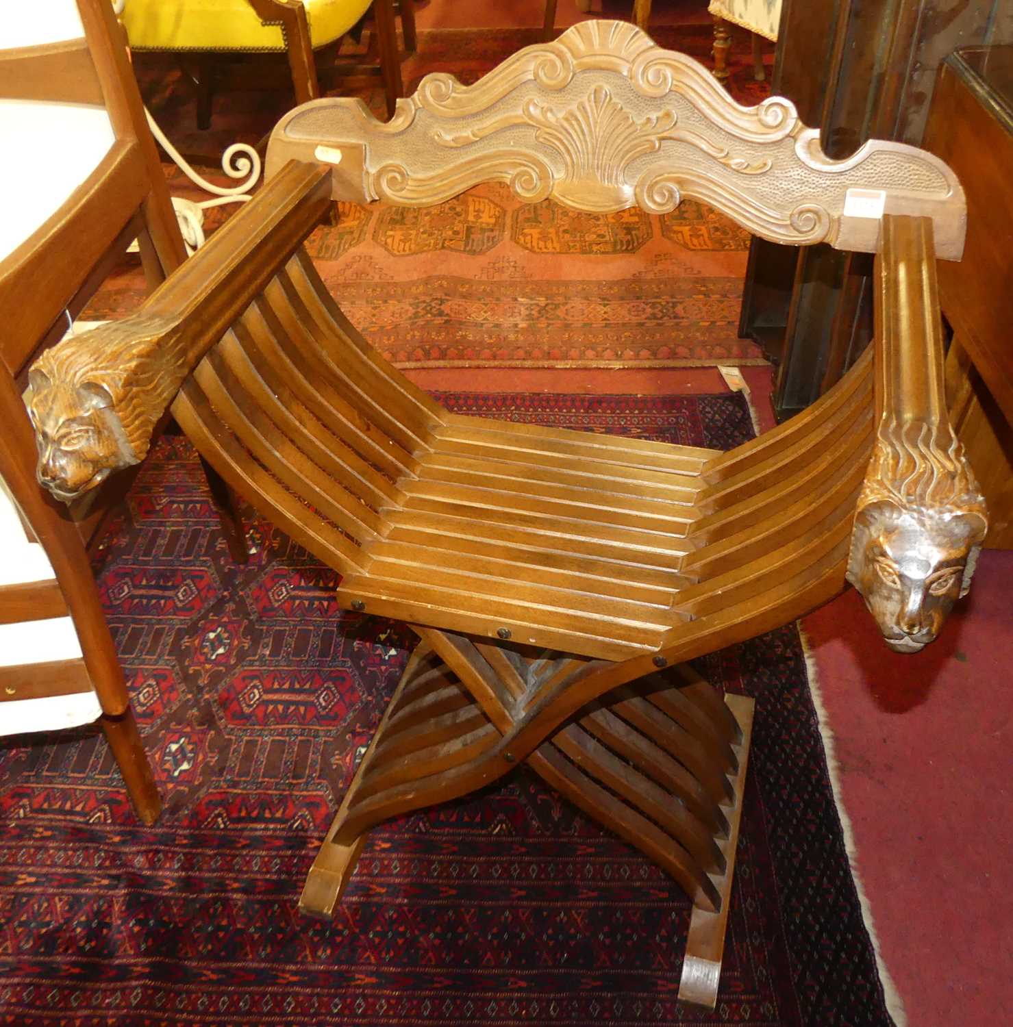 A pair of contemporary Spanish stained hardwood X-frame folding elbow chairs, with lion mask