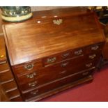 A George III mahogany slopefront writing bureau, having a well fitted interior over three short