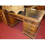 A late Victorian oak and rexine inset twin pedestal writing desk, having typical arrangement of nine