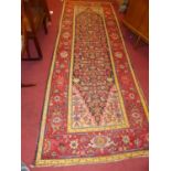 A Turkish woollen red ground long hall runner, having all-over geometric floral decorated ground,