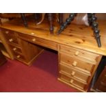 A modern pine round cornered kneehole writing desk, having an arrangement of nine drawers, w.152cm