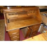 An early 20th century oak kneehole roll top desk having fitted interior, each pedestal with three