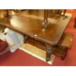 An Edwardian walnut extending dining table, having a wind-out action and two extra drop-in leaves