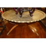 An Eastern floral low relief engraved brass circular low Benares table, raised on folding hardwood