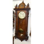 A circa 1900 walnut Vienna droptrunk wall clock, having pendulum, winding key, and two brass