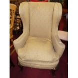 A circa 1900 walnut framed and cream floral upholstered wingback armchair, raised on acanthus leaf