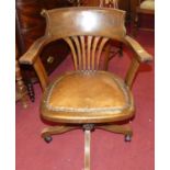 A 1930s oak tub splatback swivel desk chair, having a tan leather studded fixed pad seat and