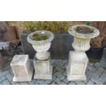 Two similar reconstituted stone circular urn planters, each on square bases; together with a further