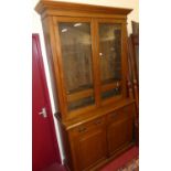 A circa 1900 oak bookcase cupboard having twin glazed upper doors with adjustable shelves over