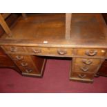 A circa 1900 walnut twin pedestal writing desk, having tan rexine inset surface over nine drawers,
