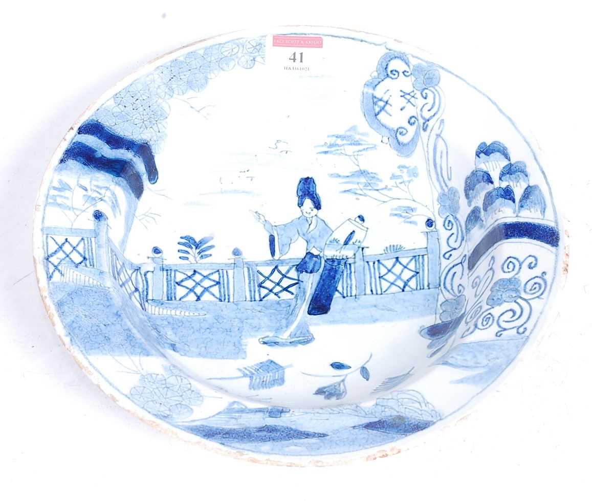 An 18th century tin-glazed dish, decorated in the Chinese taste with a figure before a fence, dia.