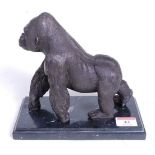 A bronzed model of a gorilla, walking on all fours, mounted upon a veined black marble plinth, h.