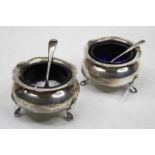 A pair of early 20th century silver open salts of squat circular form with blue glass liners and