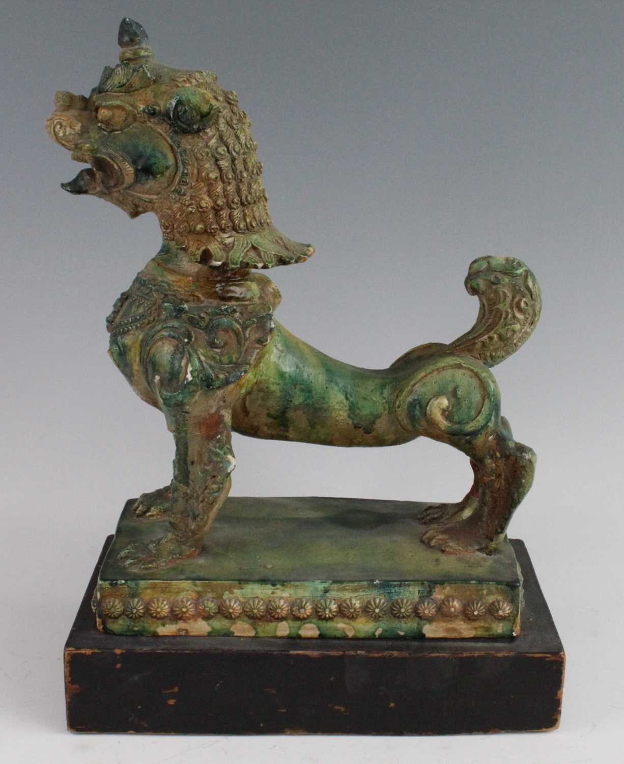 A Chinese green glazed pottery figure of a Fu Lion, modelled in proud standing pose, mounted on a